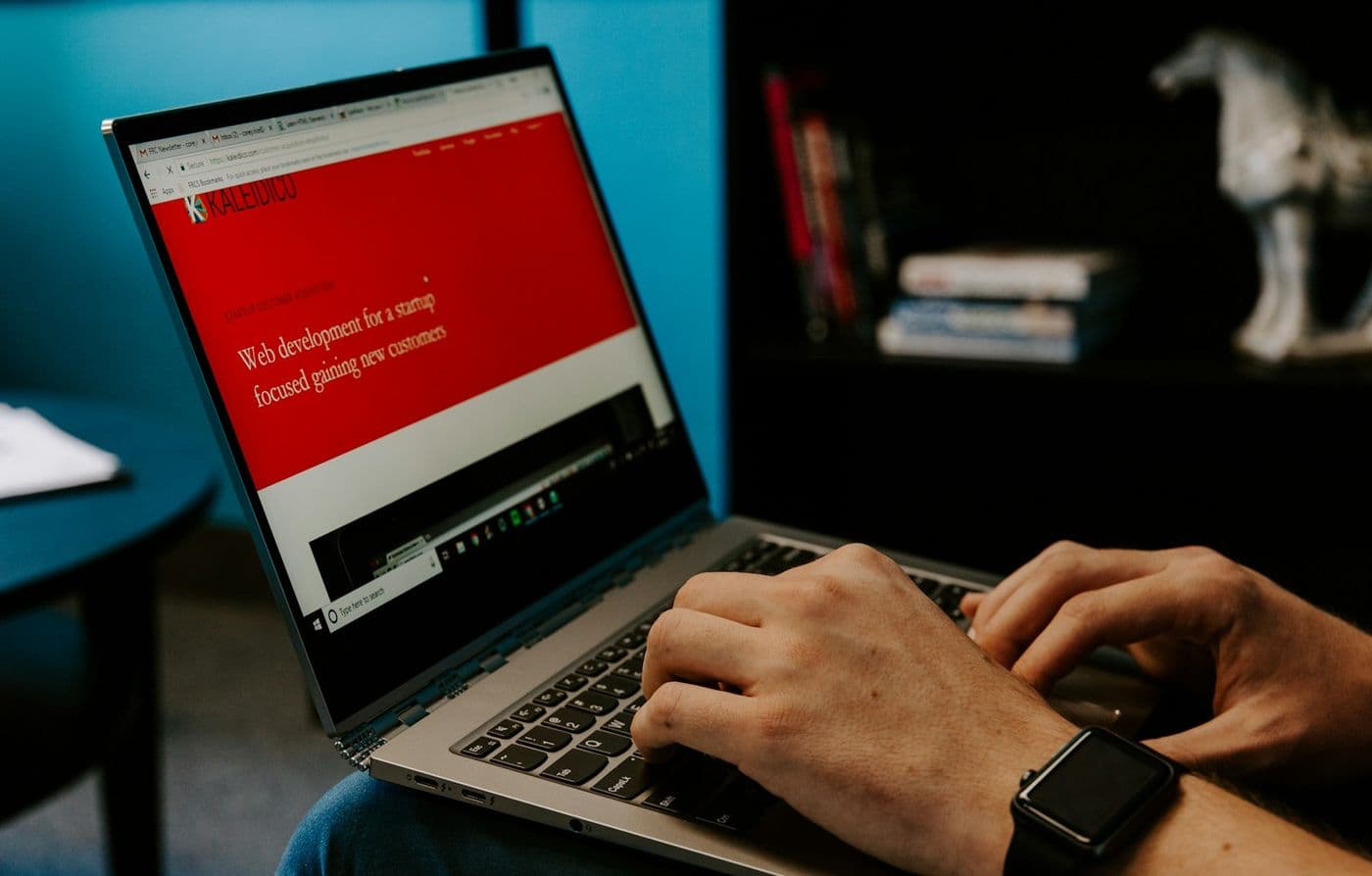 Mâini pe tastatura unui laptop cu un site deschis în browser